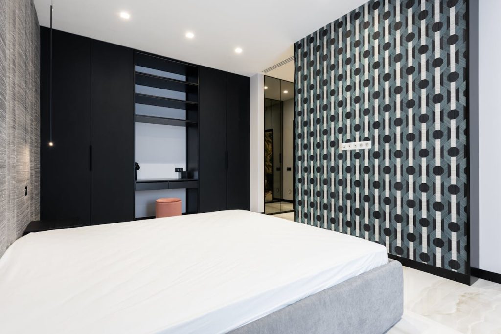 Elegant modern bedroom featuring geometric wallpaper, sleek furnishings, and minimalist design.